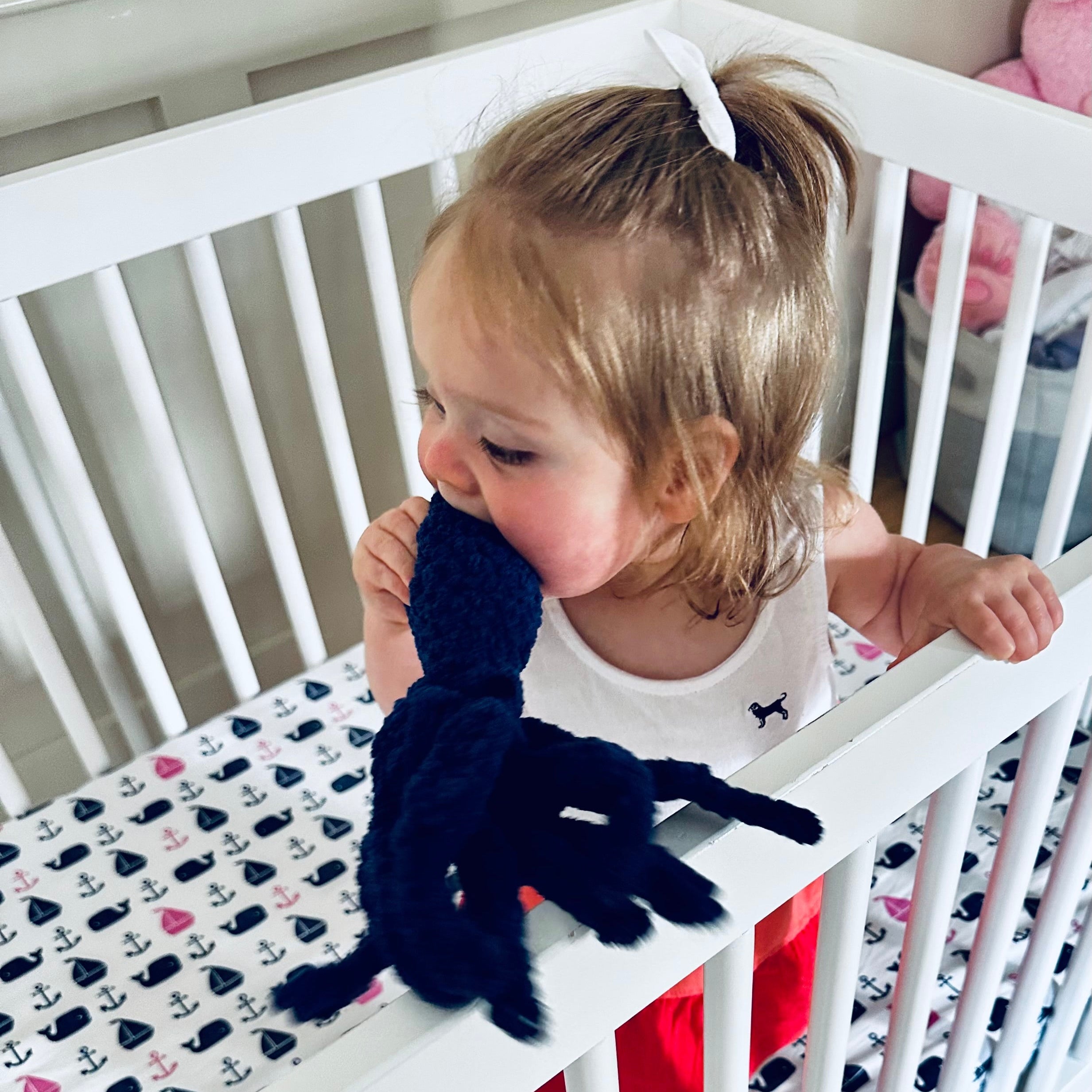 Child playing with a toy in a crib with a patterned sheet
